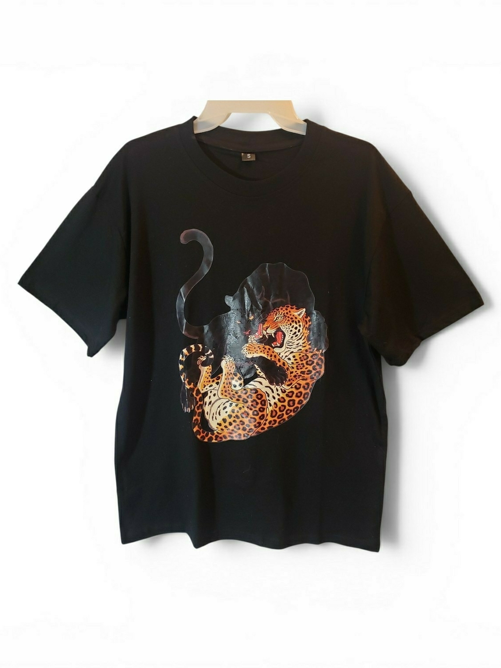 Black t-shirt features a graphic print of a panther fighting a leopard. New